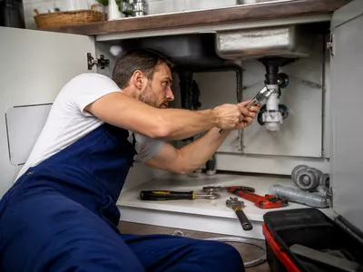 Image of a plumber working on a sink